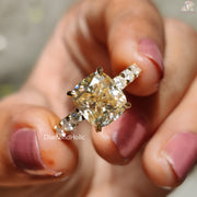 Cushion Cut Moissanite Wedding Ring with sparkling side stones held between fingers by Diamond Holic