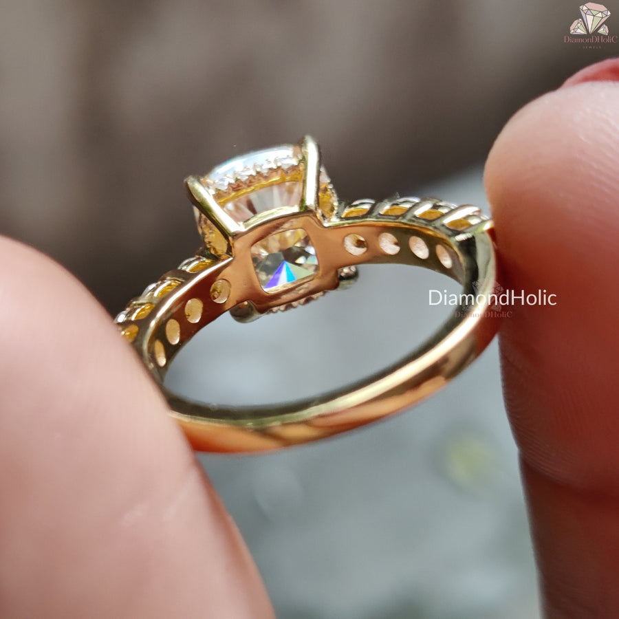 Gold Cushion Cut Moissanite Wedding Ring held between fingers showing intricate setting