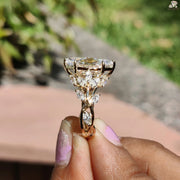 Gold ring featuring a large Marquise Diamond surrounded by smaller diamonds held by hand