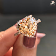 Close-up of a person holding a diamond ring with a brownish-orange center stone.