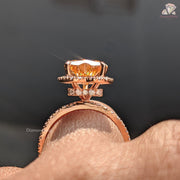 Rose gold ring with a large orange gemstone on a finger against a dark background