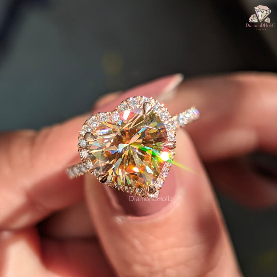 Close-up of a person holding a heart-shaped diamond ring with a blurred background